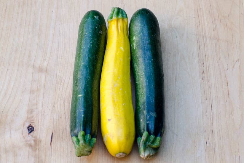 Green and yellow zucchini on a cutting board.