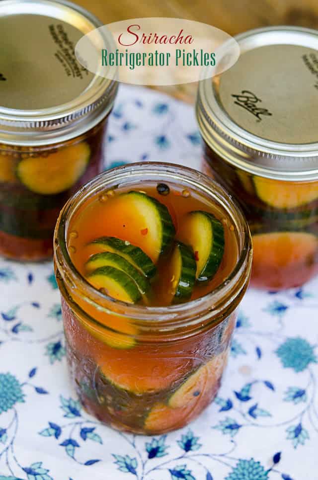 A mason jar filled with pickles in a reddish brine.