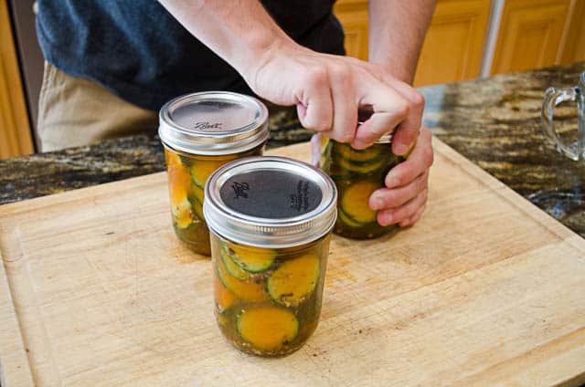 Ryan screws the lids on to the mason jars full of Sriracha Refrigerator Pickles.