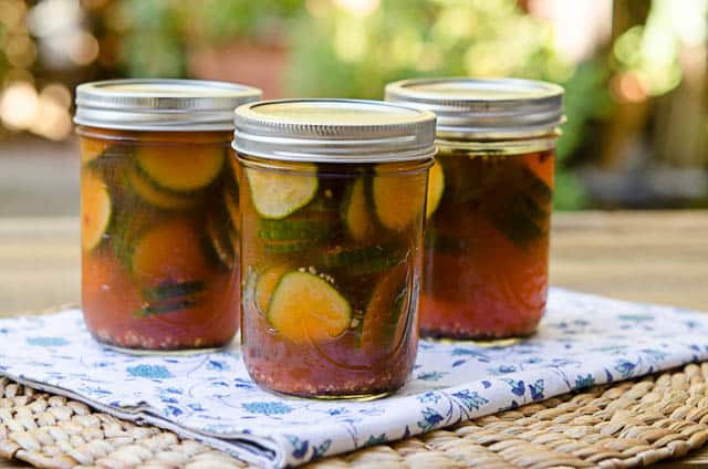 Three pints of Sriracha Refrigerator Pickles on a flowered napkin.