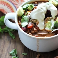 A mug filled with chili and toppings.