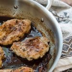 Chicken cooks in sauce in a skillet.