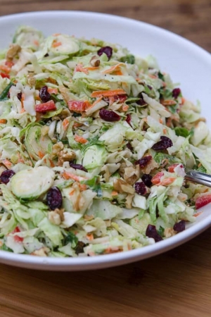 A white bowl filled with cranberry walnut coleslaw.
