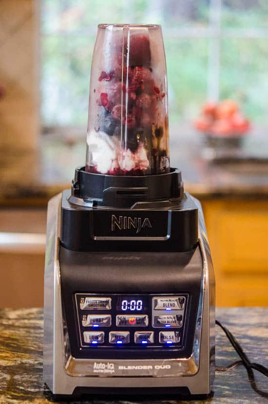 A blender cup filled with smoothie ingredients being processed.