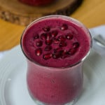 A purple smoothie topped with pomegranate seeds.
