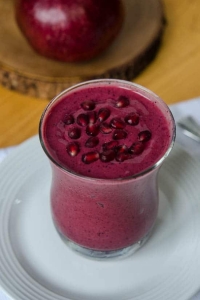 A purple smoothie topped with pomegranate seeds.