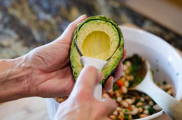 Using an avocado tool to slice the avocado.