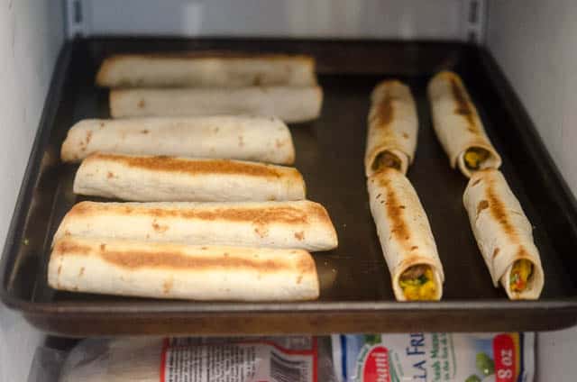 Crispy Baked Breakfast Taquitos on a baking sheet in the freezer.