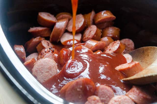 Sauce is poured over sausage in a crock pot.