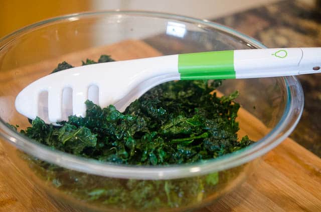 The kale in a salad bowl with tongs.