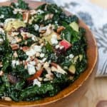 A wooden bowl filled with kale salad.