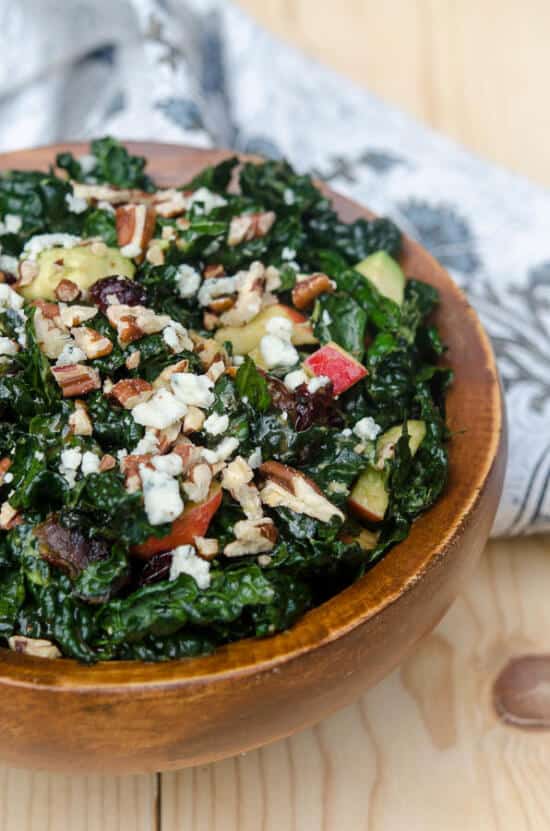 A wooden bowl filled with kale salad.