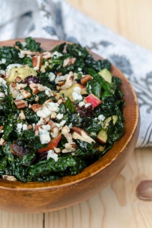 A wooden bowl filled with kale salad.