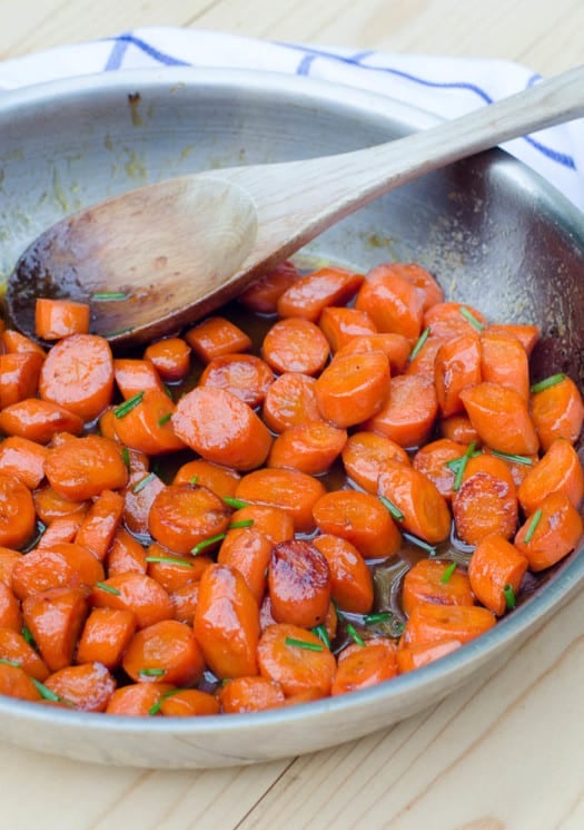 Bourbon Glazed Carrots in a skillet with a wooden spoon.