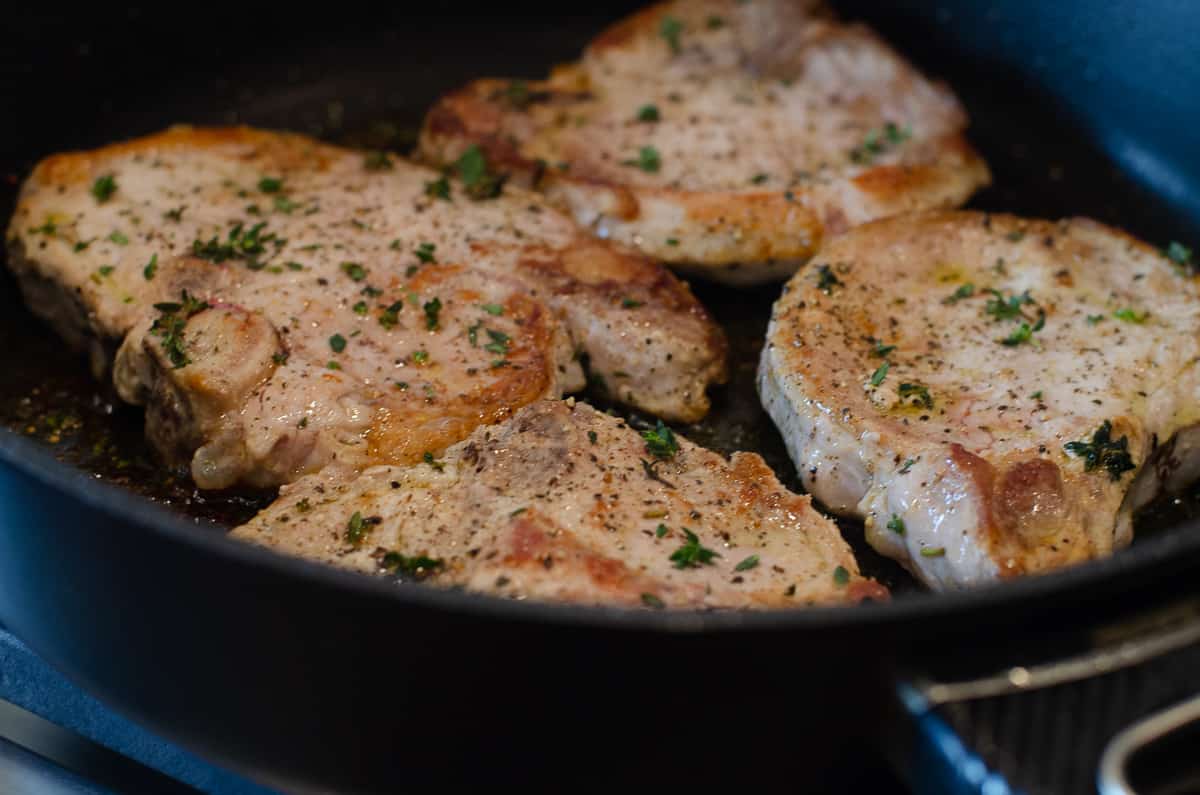 Seasoned cooked pork chops in a skillet.