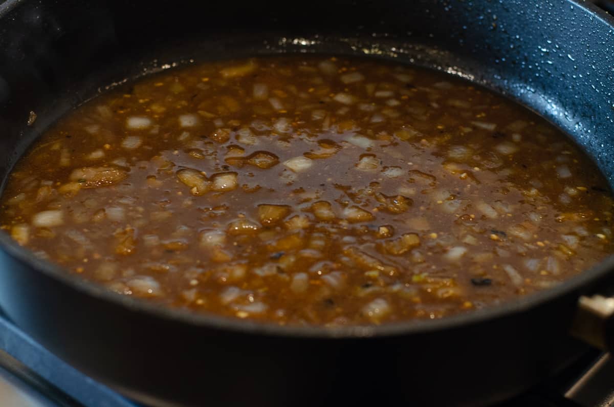 Sauce with onions simmering in a skillet.