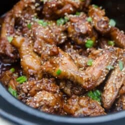 Asian BBQ Wings topped with sesame seeds and green onion in a slow cooker.
