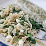 Orzo with spinach and feta on a white plate.
