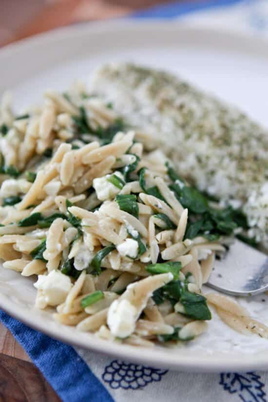 Orzo with spinach and feta on a white plate.
