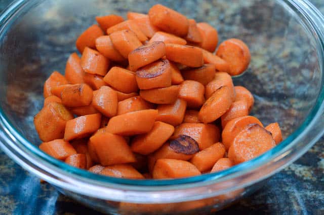 Cooked carrots in a glass mixing bowl.