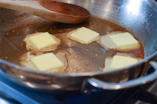 Pats of butter melting in a skillet.