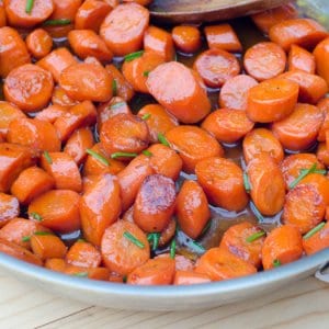 Glazed carrots topped with chives in a skillet with sauce.