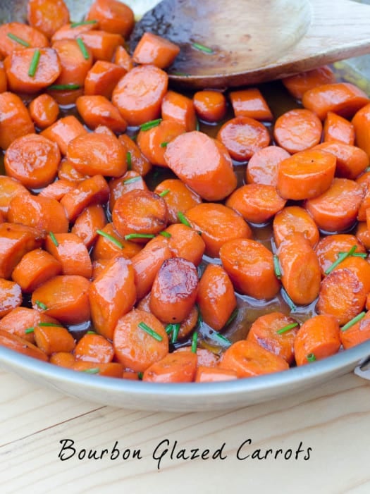 Bourbon Glazed Carrots in a skillet with a wooden spoon.