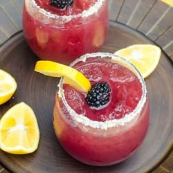 Two stemless glasses filled with blackberry lemonade margaritas.