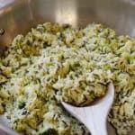 A wooden spoon scooping up wild rice with broccoli and cheese.