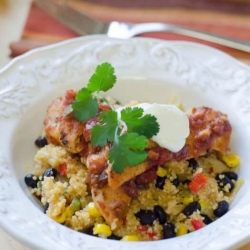 A bowl filled with couscous, black beans, and veggies, topped with chicken.