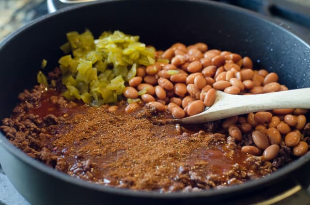 Diced green chilis, beans, seasoning added to the skillet.