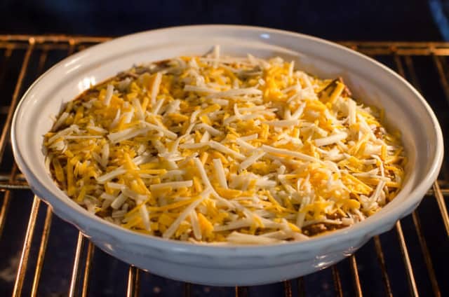 Beef Enchilada Dip in a white serving dish in the oven.