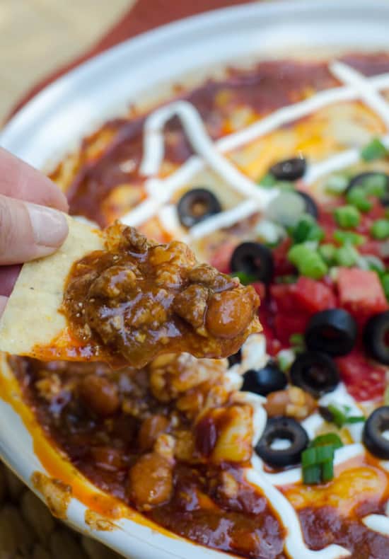 Beef Enchilada Dip being scooped up with a tortilla chip.
