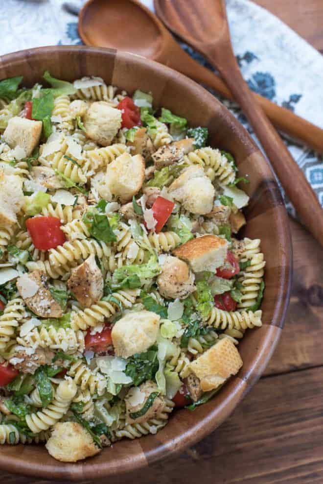 Chicken Caesar Pasta Salad in a wooden serving bowl with salad spoons.
