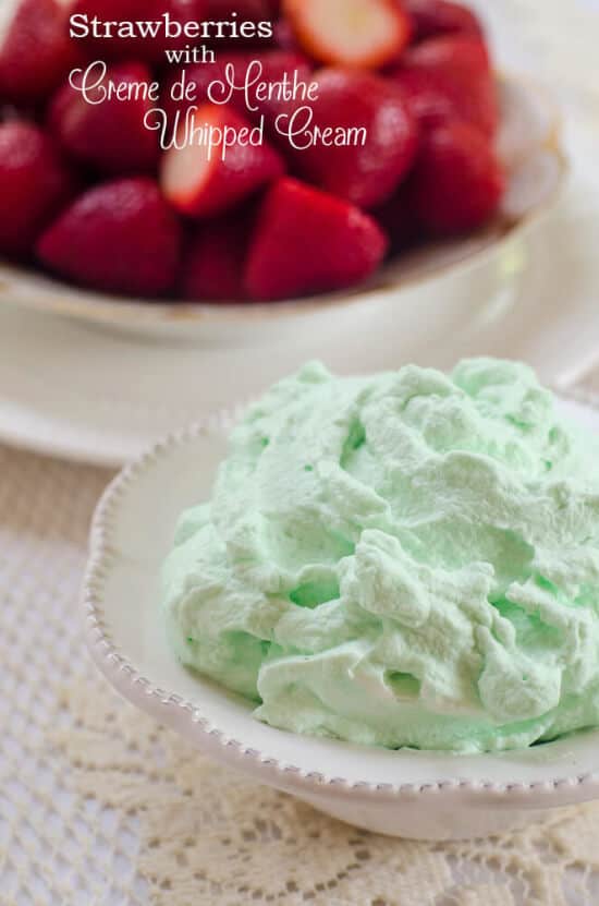 A bowl filled with green whipped cream with strawberries in the background.