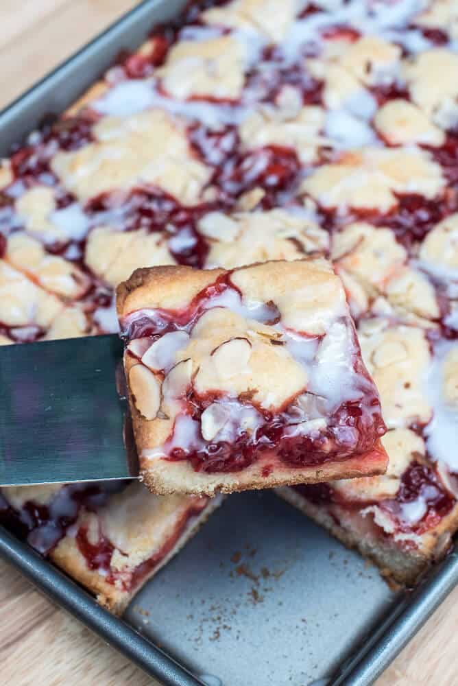 A spatula lifts a Cherry Pie Bar from the baking dish.