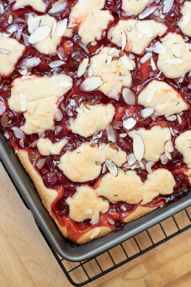 A close up of the Cherry Pie Bars cooling on a wire rack after they come out of the oven.