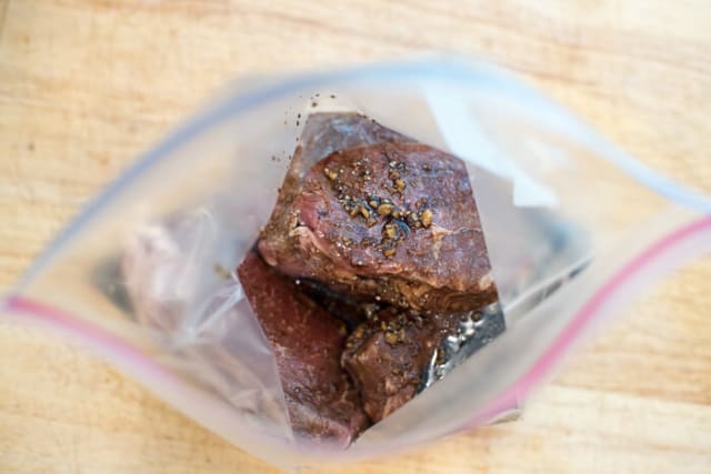 Steak and marinade in a plastic storage bag.