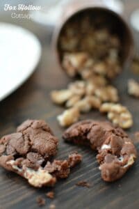 Rocky Road Cookies broken in half on a dark wood board with nuts in the background.
