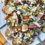 Steak salad with roasted potatoes on a white platter.