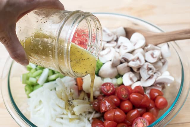 Italian dressing pours from a mason jar on to the salad.