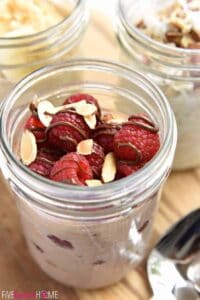 Overnight oats in a mason jar topped with raspberries, almonds, and chocolate.