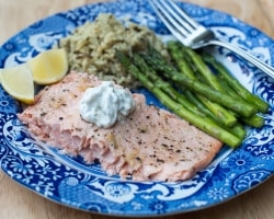 Salmon topped with a creamy sauce on a blue plate.