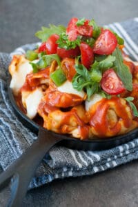 Tortellini with sauce, cheese, tomatoes, and basil in a cast iron skillet.