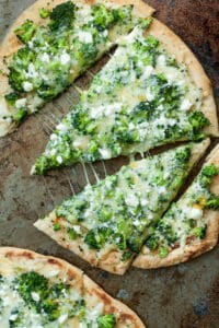 Broccoli cheese pizza slices on a baking sheet.