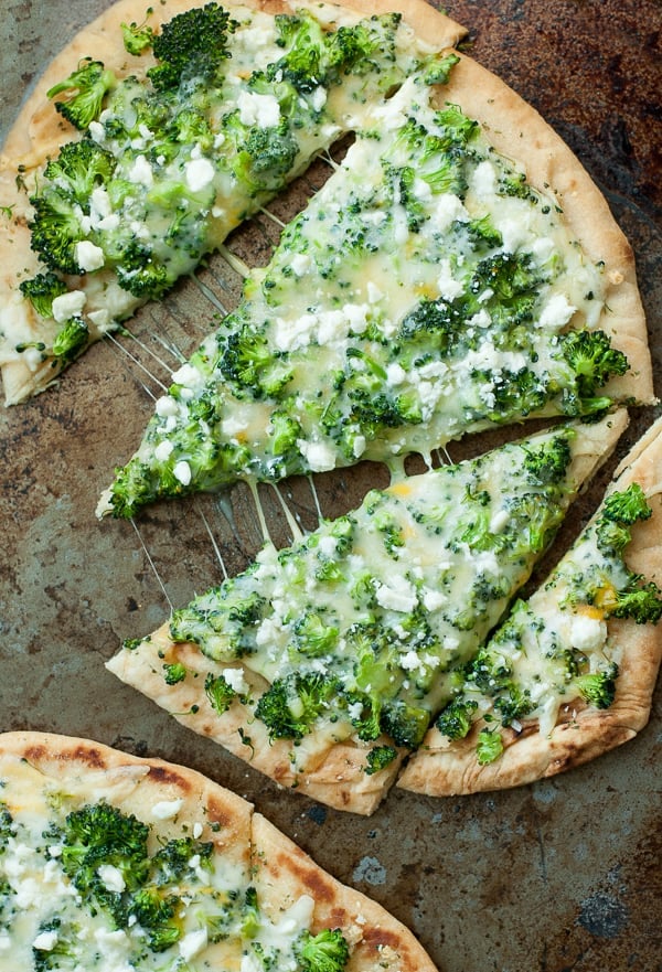 Broccoli cheese pizza slices on a baking sheet.