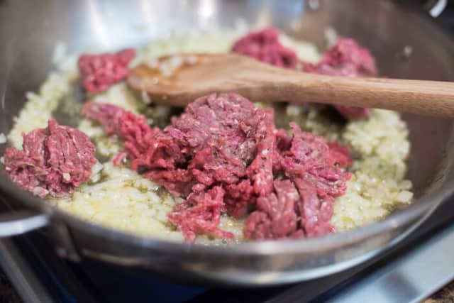 Ground beef and onion cooking in a skillet.