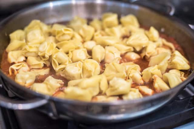 Cheese tortellini is added to the skillet.