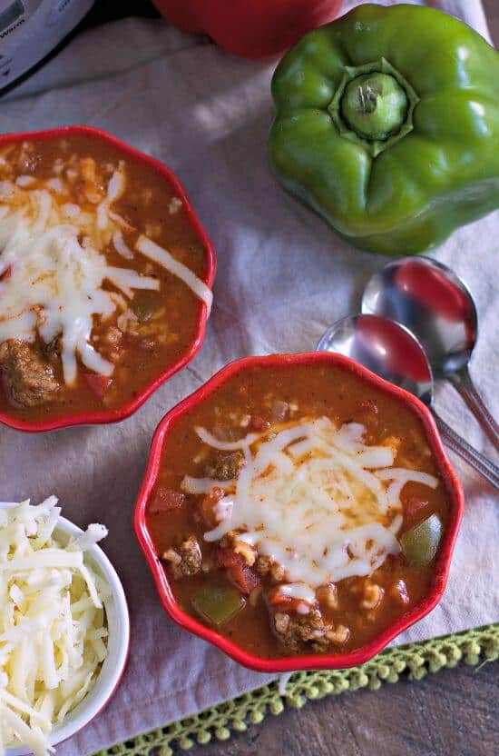 Slow Cooker Stuffed Pepper Soup in red serving bowls with melted cheese.