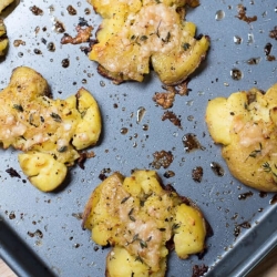 A baking dish filled with roasted smashed potatoes.